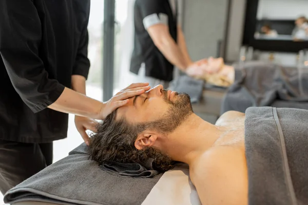 Двоє масажів роблять масаж на обличчі парі в салоні Спа. — стокове фото