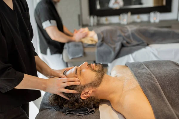 Двоє масажів роблять масаж на обличчі парі в салоні Спа. — стокове фото