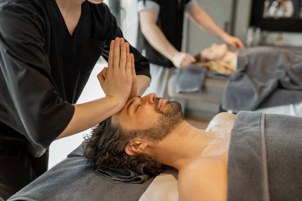 Spa salonunda erkek bir müşteriye yüz masajı yapan profesyonel bir kadın masör. — Stok fotoğraf