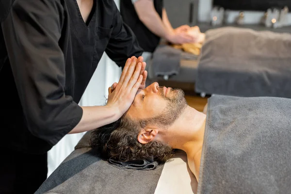 Two masseurs doing facial massage to a couple at Spa salon — Stock Photo, Image