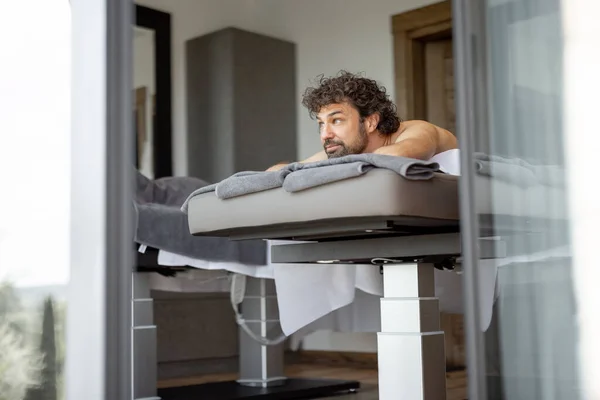 Schöner Mann liegt im Wellness-Salon und wartet auf Rückenmassage — Stockfoto