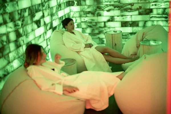 Duas mulheres de roupão sentado e relaxante na sala de sal — Fotografia de Stock