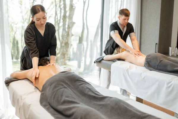 Два масажиста роблять глибокий масаж спини для гостей — стокове фото