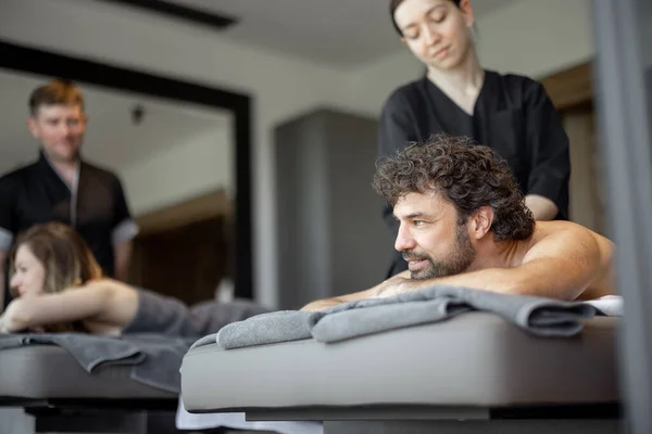 Beautiful couple lying in a spa salon enjoying getting deep back massage and relaxation. — Stock Photo, Image