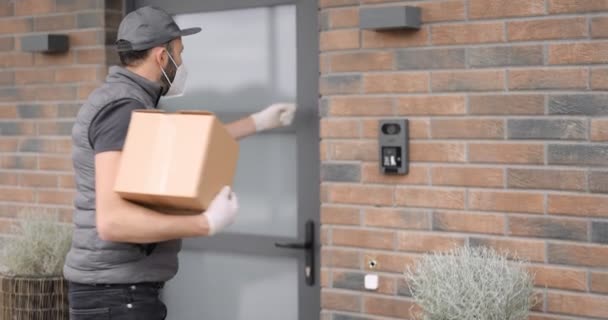 Courier in face mask delivers parcels home — Vídeos de Stock