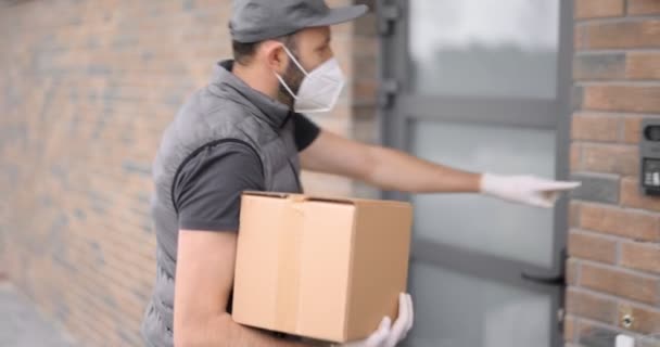 Courier na máscara facial entrega pacote para uma jovem mulher para casa — Vídeo de Stock