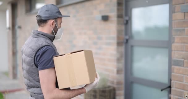 Corriere in maschera consegna pacco per una giovane donna a casa — Video Stock