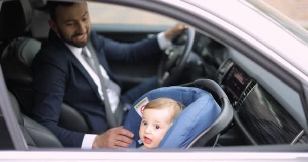 Businessman drives at work with his one year boy fastened in baby chair — Stock Video