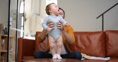 Orta yaşlı baba yeni doğmuş bebeği taşıyor ve onunla oynuyor.