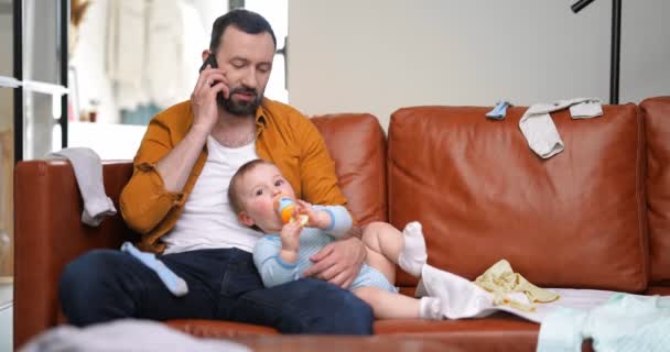 Padre stanco che allatta un neonato a casa — Video Stock