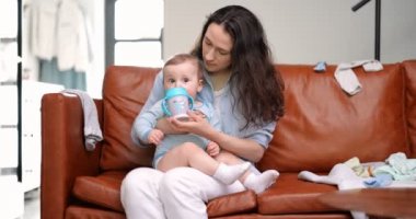 Anne bir yaşındaki bebeğini biberonla besler.