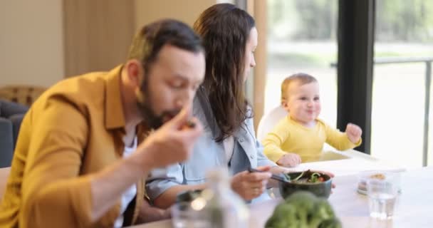 Familia joven con un niño de un año durante un almuerzo en casa — Vídeos de Stock