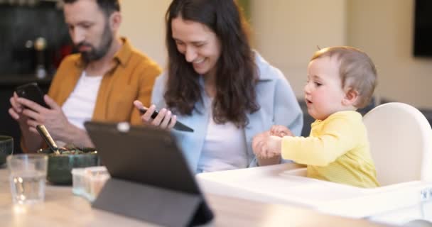 Μωρό και οι γονείς απασχολημένος σε ένα ψηφιακό gadgets κατά τη διάρκεια ενός γεύματος στο σπίτι — Αρχείο Βίντεο