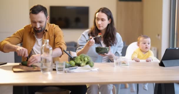 Młoda rodzina z rocznym synkiem podczas lunchu w domu — Wideo stockowe