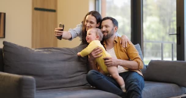 Familia feliz con un bebé de un año teniendo una videollamada en el teléfono — Vídeos de Stock