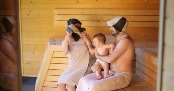 Familia joven con un niño pequeño en sauna — Vídeo de stock