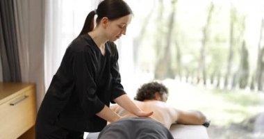 Kadın masör erkek müşteriye masaj yapıyor.