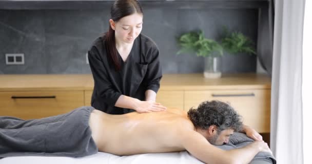 Женщина-массажистка делает массаж клиенту-мужчине — стоковое видео