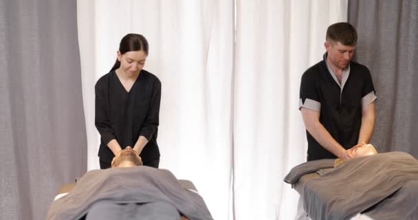 Spa 'da bir çifte yüz masajı yapan iki masör. — Stok video