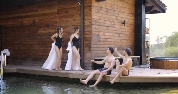 Vrienden op het terras in de buurt van het buitenzwembad in spa — Stockvideo