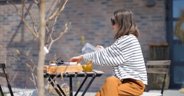 Vrouw ontbijten met croissants en koffie buiten — Stockvideo