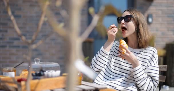 Mulher tomando um café da manhã com croissants e café ao ar livre — Vídeo de Stock