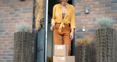 Kadın evinin verandasına paket alıyor.