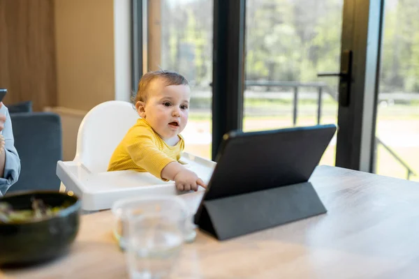 Barn og foreldre som er opptatt i en digital innretning under en lunsj hjemme – stockfoto