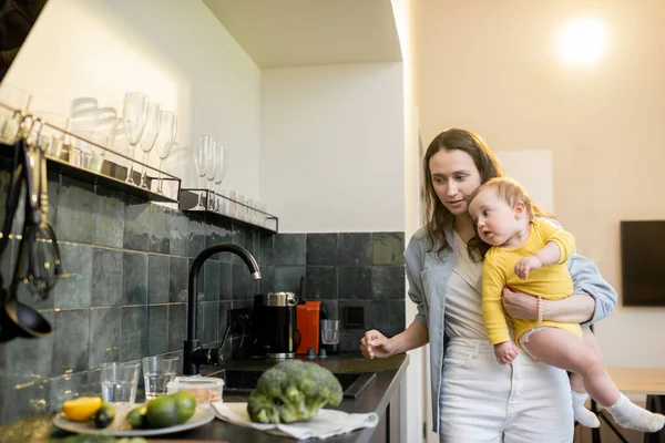 Žena zaneprázdněná domácími pracemi při kojení svého dítěte — Stock fotografie