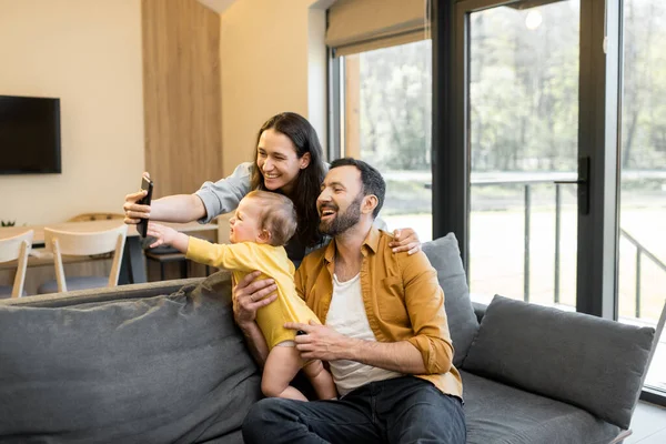 Bir yıllık bebeği olan mutlu bir aile telefonda video görüşmesi yapıyor. — Stok fotoğraf