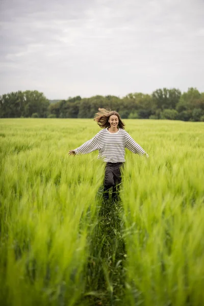 Ontspannen vrouw staat in het groene veld en geniet van kalme natuur — Stockfoto