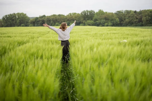 Uvolněná žena stojící na zeleném poli a má klidnou přírodu — Stock fotografie