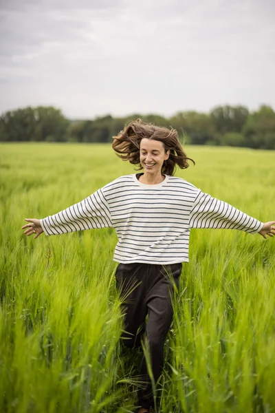 Ontspannen vrouw staat in het groene veld en geniet van kalme natuur — Stockfoto