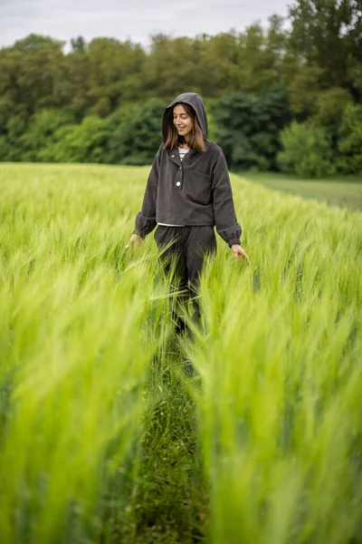 Avslappnad kvinna står i grönt fält och njuter av lugn natur — Stockfoto