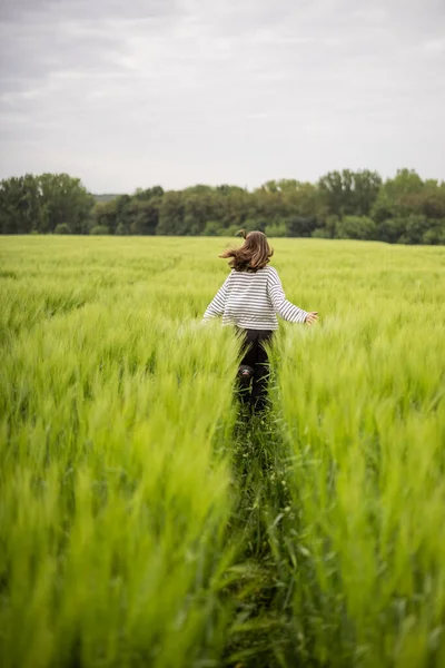 Ontspannen vrouw staat in het groene veld en geniet van kalme natuur — Stockfoto