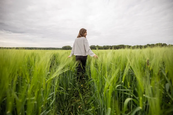 Ontspannen vrouw staat in het groene veld en geniet van kalme natuur — Stockfoto