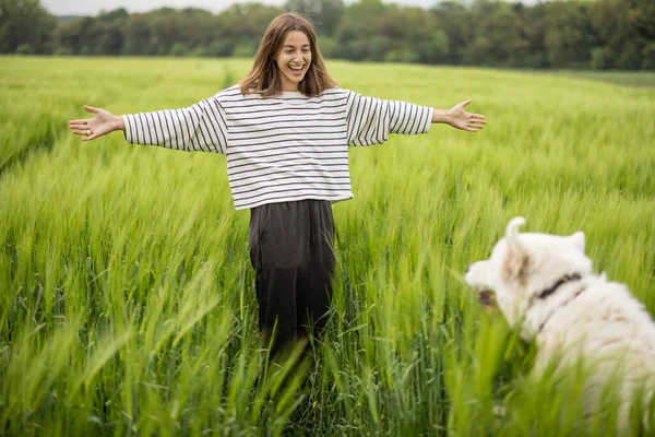 Femme avec grand chien de berger blanc marchant sur le champ de seigle vert — Photo