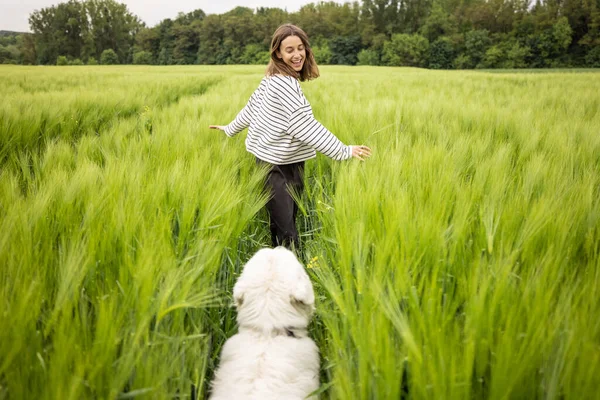 Femme avec grand chien de berger blanc qui court sur le champ de seigle vert — Photo