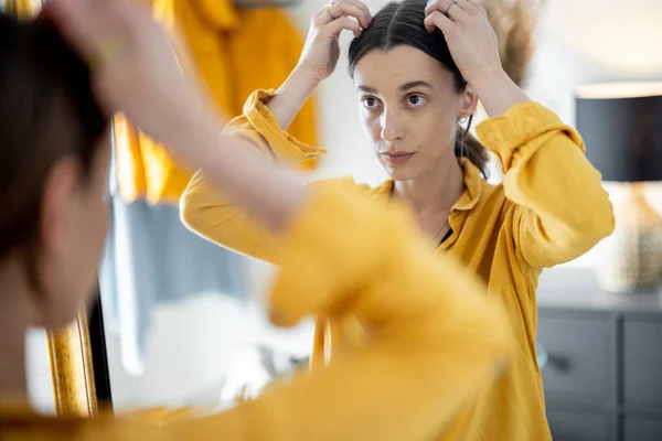 La mujer se mira en el espejo, preparándose para salir —  Fotos de Stock