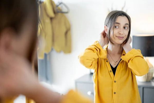 Frau blickt in den Spiegel und macht sich bereit, rauszugehen — Stockfoto