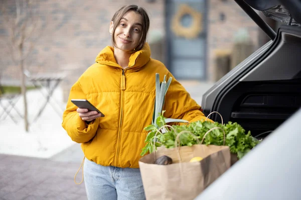 Woman arrives home by car with a groceries