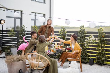 Genç arkadaşlar kır evinin arka bahçesinde yemek yiyorlar.