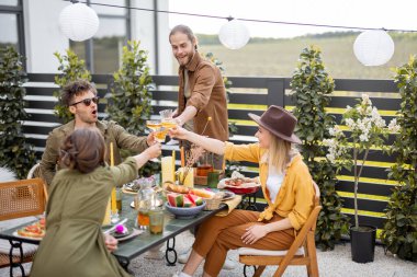 Genç arkadaşlar kır evinin arka bahçesinde yemek yiyorlar.