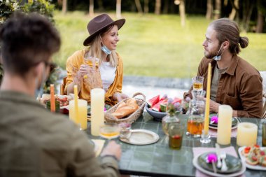 Genç arkadaşlar kır evinin arka bahçesinde yemek yiyorlar.