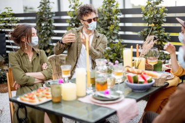 Dışarıda maskeli arkadaşlar yemek yiyor.