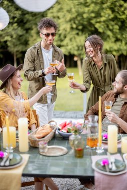 Genç arkadaşlar doğadaki kır evinin arka bahçesinde yemek yiyorlar.