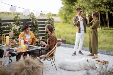 Genç arkadaşlar kır evinin arka bahçesinde yemek yiyorlar.