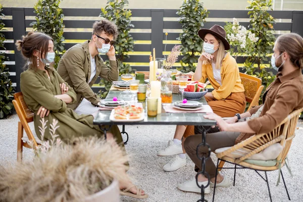 Θλιμμένοι φίλοι με μάσκα προσώπου γευματίζουν μαζί στην αυλή. — Φωτογραφία Αρχείου