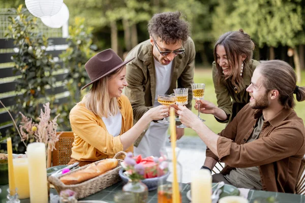 Jóvenes amigos cenando en el patio trasero de la casa de campo en la naturaleza —  Fotos de Stock