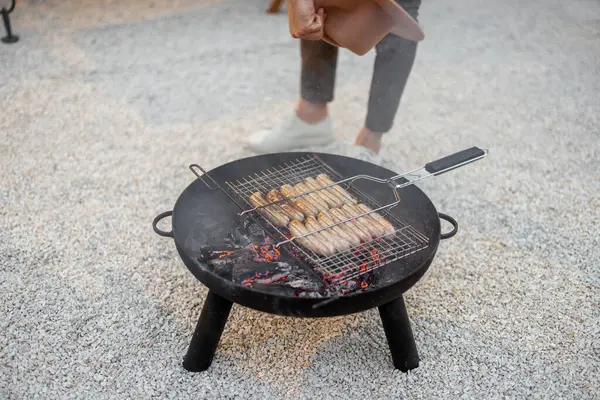 Man grillen worsten op een bbq kom — Stockfoto